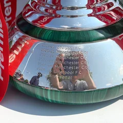 The trophy base inscribed with the recent winners of the Premier League, including Arsenal for 2025-26.