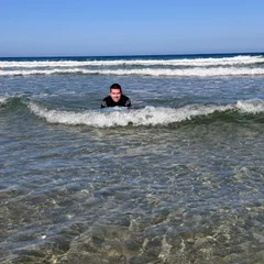 Man in wetsuit lying on a bodyboard on a beach